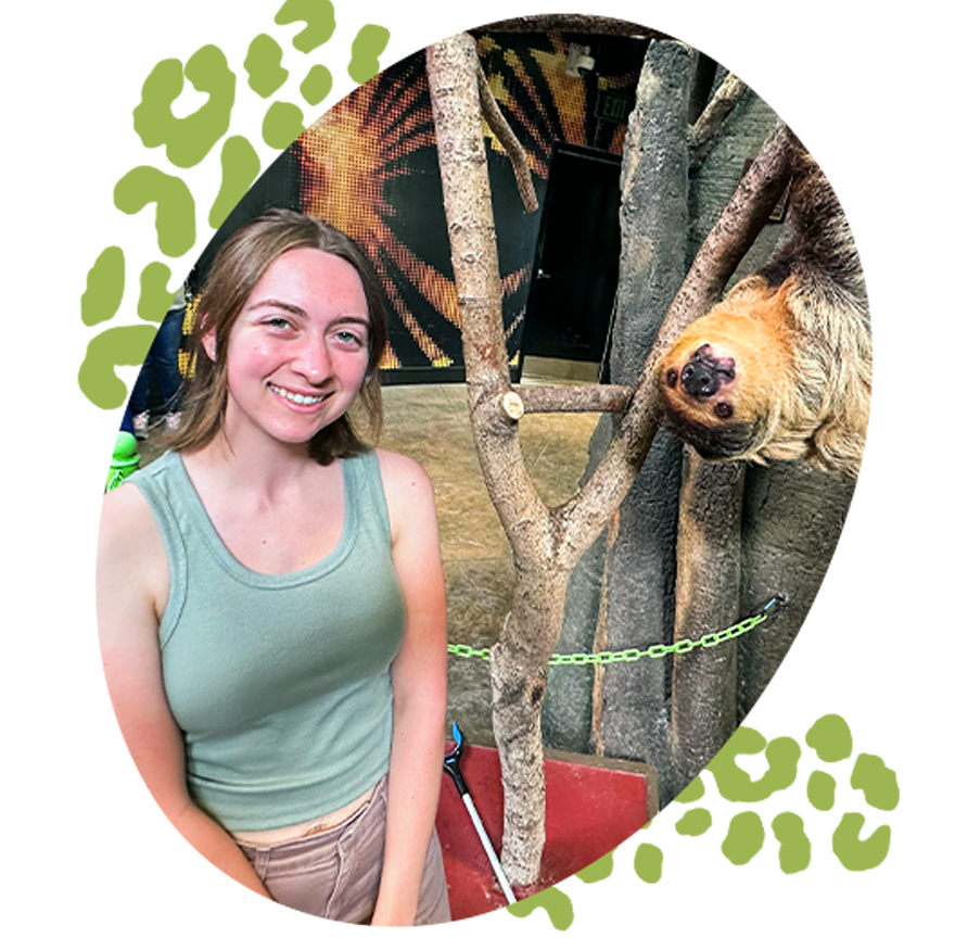 Woman smiling and standing next to sloth.